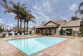 Woodland apartment for rent - A large outdoor swimming pool surrounded by palm trees and a building.