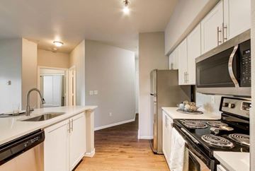 Gresham apartment for rent - A kitchen with white cabinets and black appliances.