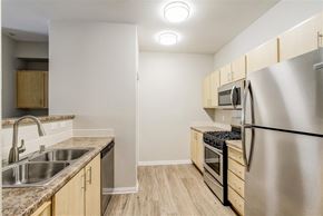 Turlock apartment for rent - A kitchen with a stainless steel refrigerator, sink, and wooden cabinets.
