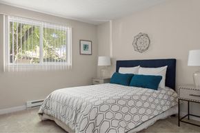 Portland apartment for rent - A bedroom with a large bed and a window with blinds.