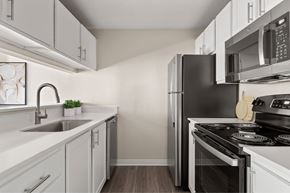University Place apartment for rent - A kitchen with white cabinets and a black refrigerator.