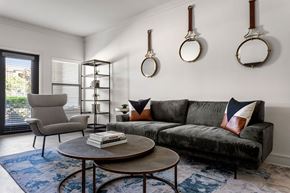Fort Worth apartment for rent - A living room with a grey couch, a grey chair, a coffee table, and a book on it.