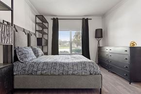 Fort Worth apartment for rent - A bedroom with a large bed, a dresser, and a window with black curtains.