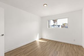 National City apartment for rent - A room with wooden flooring and a window showing a view of a street with buildings and a palm tree.