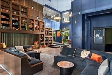 Austin apartment for rent - A modern living room with a dark blue couch and a wooden bookshelf.
