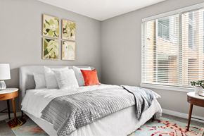 Austin apartment for rent - A bedroom with a large bed and a window with blinds.