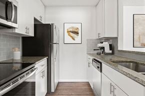 Austin apartment for rent - A kitchen with white cabinets and a black refrigerator.