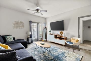 Panama City Beach apartment for rent - A living room with a blue rug and a black sofa.