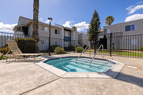 Ramona apartment for rent - A pool surrounded by a black fence with a chair and a tree in the background.