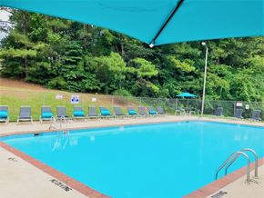 Raleigh apartment for rent - A pool with a blue umbrella and chairs around it.