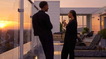 Two people standing outside a house at sunset.
