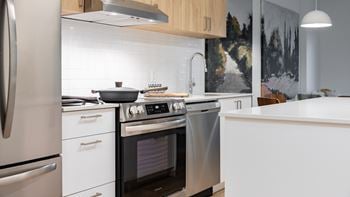 A modern kitchen with a stainless steel oven and white cabinets.