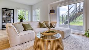 Gatineau apartment for rent - A living room with a beige couch, a wooden coffee table, and a staircase in the background.