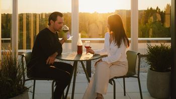 A man and a woman are sitting at a table with drinks, enjoying a conversation.