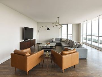 Ottawa apartment for rent - A living room with a brown sofa and a television on the wall.