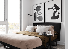 Gatineau apartment for rent - A bedroom with a bed, a table with a glass, a candle, and a plate, and two posters on the wall.