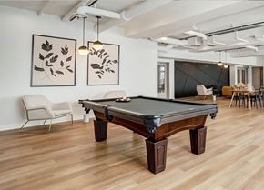 Ottawa apartment for rent - A pool table is in the middle of a room with a chair and a painting on the wall.