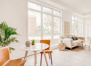 Ottawa apartment for rent - A living room with a white table and chairs, a couch, and a plant.
