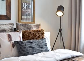 Gatineau apartment for rent - Cozy bedroom with decorative pillows and tripod lamp at Jardins McConnell Apartments, Gatineau