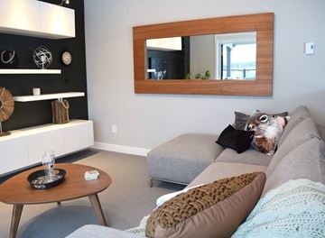 Gatineau apartment for rent - A living room with a grey couch, a brown pillow, a wooden coffee table and a mirror on the wall.
