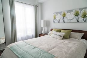 Ottawa apartment for rent - A bedroom with a bed, a lamp, and a painting on the wall.