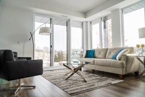 Ottawa apartment for rent - A modern living room with a black chair, a beige couch, and a glass coffee table.