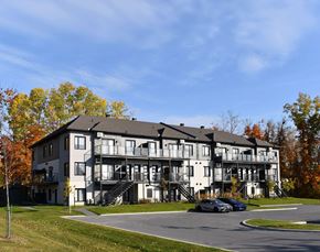 Gatineau apartment for rent - A large white building with a black roof and a balcony on the second floor.