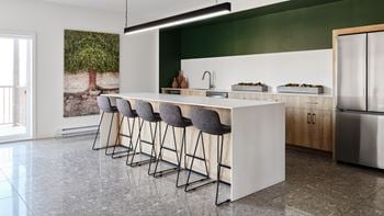 A modern kitchen with a long white island and grey bar stools.