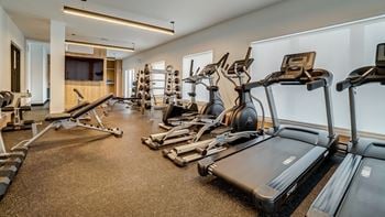 A spacious gym with treadmills, elliptical machines, and other exercise equipment.
