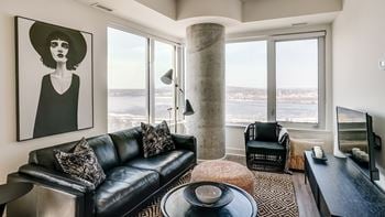 A living room with a black couch and a large window.