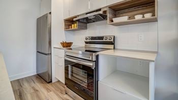 A modern kitchen with a stainless steel refrigerator, oven, and white cabinets.