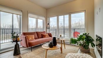 A living room with a pink couch, a black vase, and a wooden coffee table.