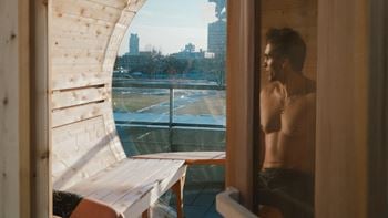 A man stands in front of a window looking out at a cityscape.