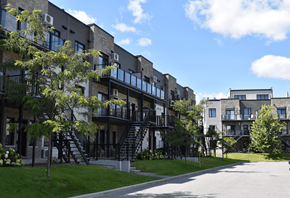 Gatineau apartment for rent - Apartment buildings with balconies and staircases are surrounded by green grass and trees.