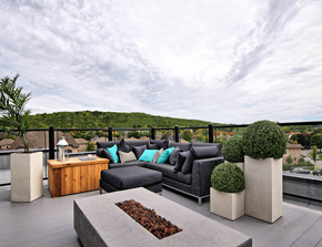 Gatineau apartment for rent - A modern outdoor patio with a black couch, wooden table, and concrete planters.