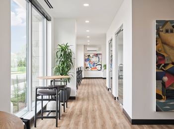 A long hallway with a table and chairs on the left and a painting on the right.