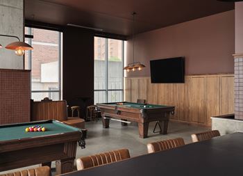 A pool table with a green cloth and a television mounted on the wall.