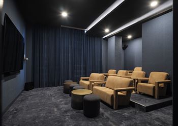 A dark room with a row of chairs and a screen on the wall.