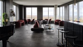 A grand piano sits in a room with a view of the city.