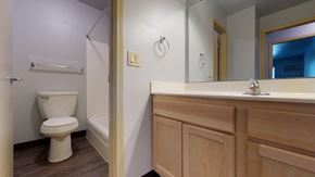 Madison apartment for rent - A white toilet is in a small bathroom with wood cabinets.