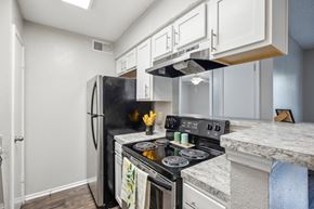 Bedford apartment for rent - A kitchen with a black fridge and stove top oven.