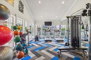Bedford apartment for rent - A gym with a variety of equipment including a rowing machine, a bench press, and a leg press.
