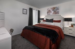 Upland apartment for rent - A bedroom with a red comforter and a white nightstand.
