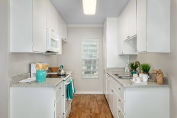 Orange apartment for rent - A kitchen with white cabinets and a blue bowl on the counter.