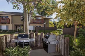 Brea apartment for rent - A BBQ grill is in the middle of a yard with a building in the background.