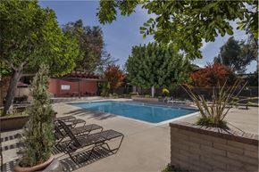 Brea apartment for rent - A pool surrounded by trees and chairs.
