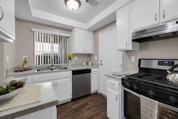 Whittier apartment for rent - A modern kitchen with white cabinets and a black stove top.