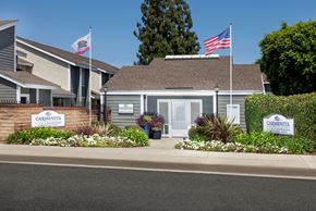 Whittier apartment for rent - The leasing office with Carmenita Townhouse Apartments signs surrounded by flowers and greenery out front.