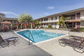 Garden Grove apartment for rent - A pool surrounded by chairs and umbrellas.