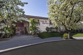 Garden Grove apartment for rent - A "Casa de Portola" sign on a building with trees in front.